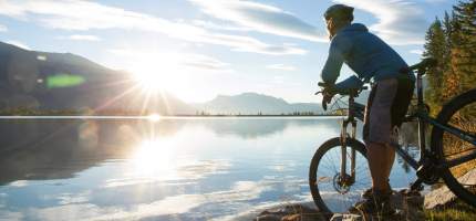 Ein Fahrradfahrer steht mit seinem Mountainbike vor einem großen See