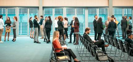 Viele Menschen befinden sich in einem Konferenzraum.