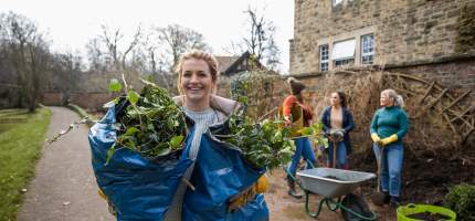 Ein junges Mädchen hilf ehrenamtlich bei der Pflege eines Mauerstücks.