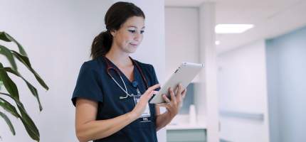 Junge Ärztin schaut im Krankenhaus auf ein Tablet.