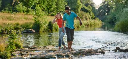 Junge Menschen gehen durch einen Fluss.