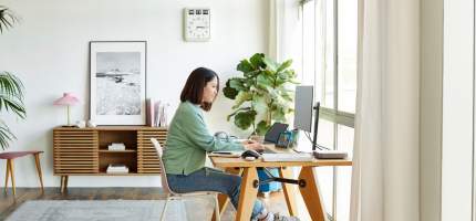 Eine Frau im Homeoffice sitzt vor einem Bildschirm.