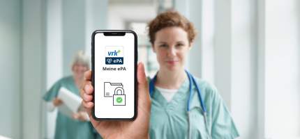 Eine Hand hält ein Handy auf welchem die VRK Meine ePA App zu sehen ist im Hintergrund ist eine Ärztin in einer Klinik zu sehen.