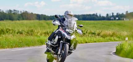 Ein Motorradfahrer auf einer Landstraße fährt um eine Kurve.