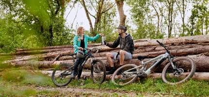 Zwei Fahrradfahrer machen eine Trinkpause im Wald.