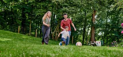 Eine Familie spielt Fußball im Garten.