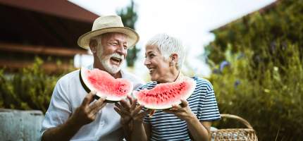 Ein älteres Paar isst Wassermelone und lacht.