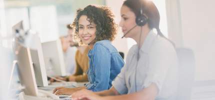 Zwei Frauen mit Headset im Büro.