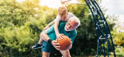 Junge spielt mit Opa Basketball.