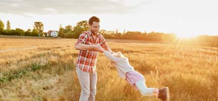 Vater spielt mit seiner Tochter auf einem Feld.