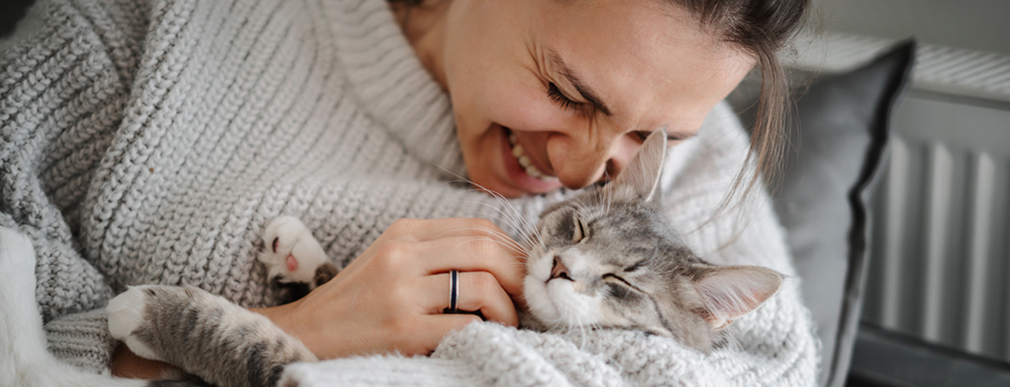 Eine Frau trägt ihre entspannte Katze in den Armen.