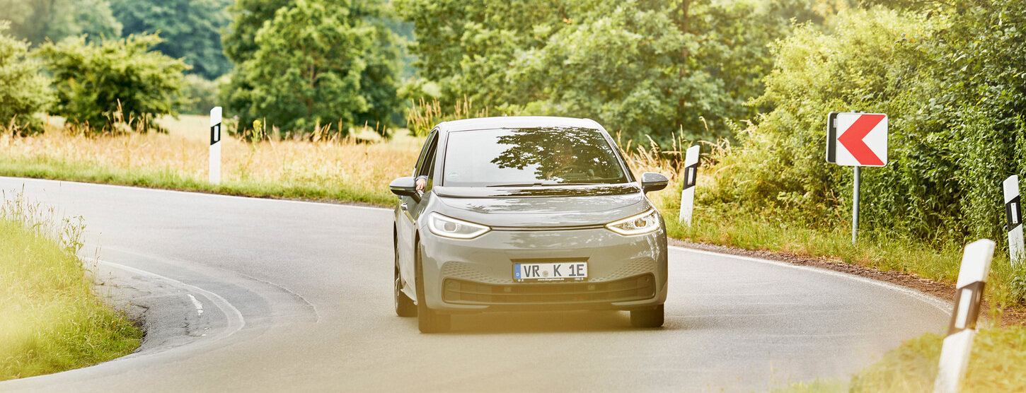 Elektroauto fährt auf einer ländlichen Straße um eine Kurve.