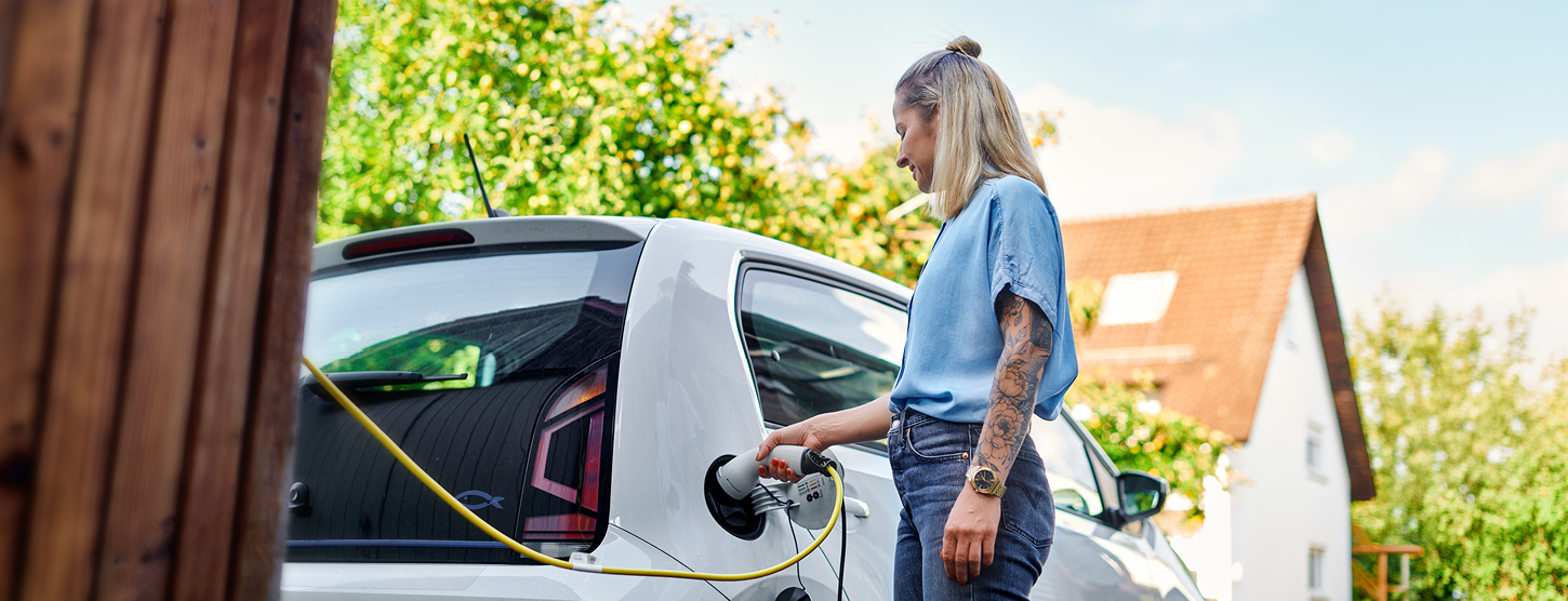 Eine junge Frau lädt ihr E-Auto.