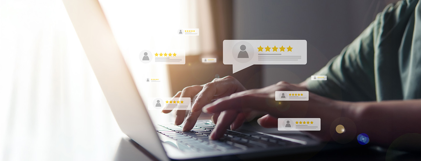 Eine Person schreibt etwas an einem Laptop. Im Vordergrund sind Bewertungen mit Sternen zu sehen.