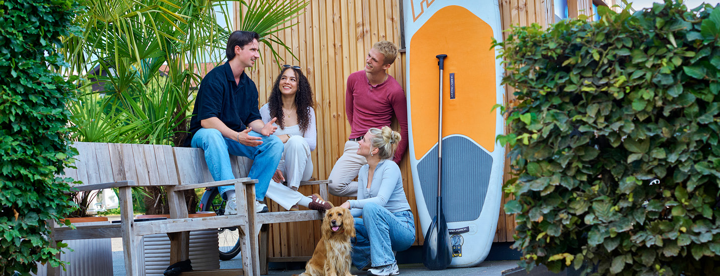 Eine Gruppe Jugendlicher, Männer und Frauen, unterhalten sich draußen zusammen.