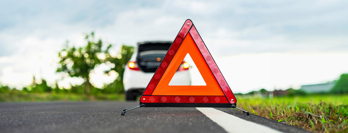 Warndreieck auf einer Landstraße hinter einem Auto.