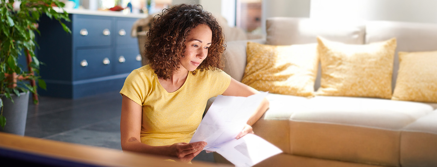 Eine junge Frau sitzt auf dem Boden und liest einen Brief.