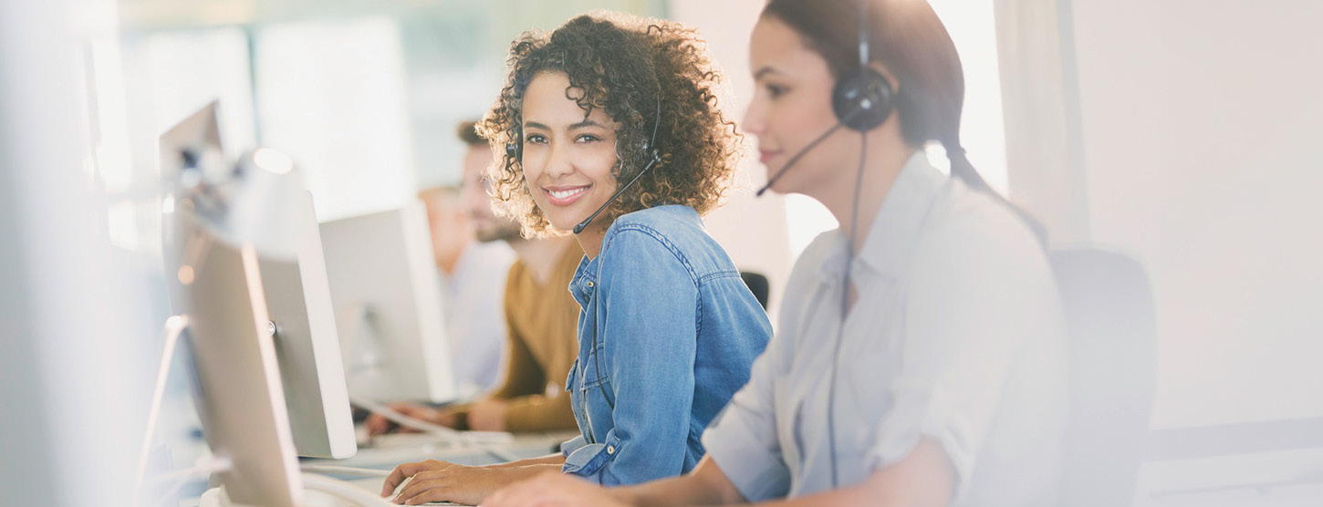 Zwei Frauen mit Headset im Büro.