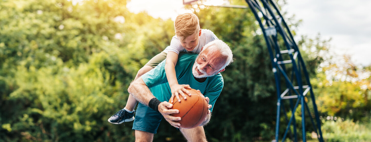 Junge spielt mit Opa Basketball.