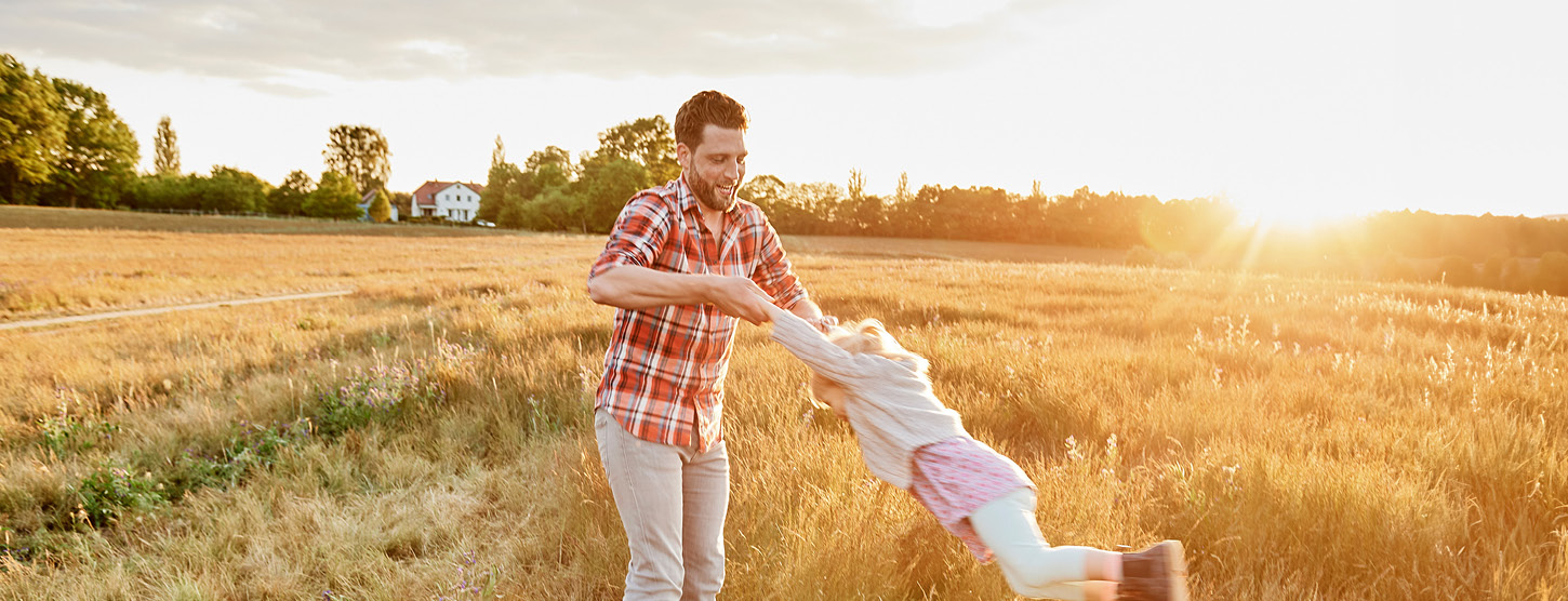 Vater spielt mit seiner Tochter auf einem Feld.