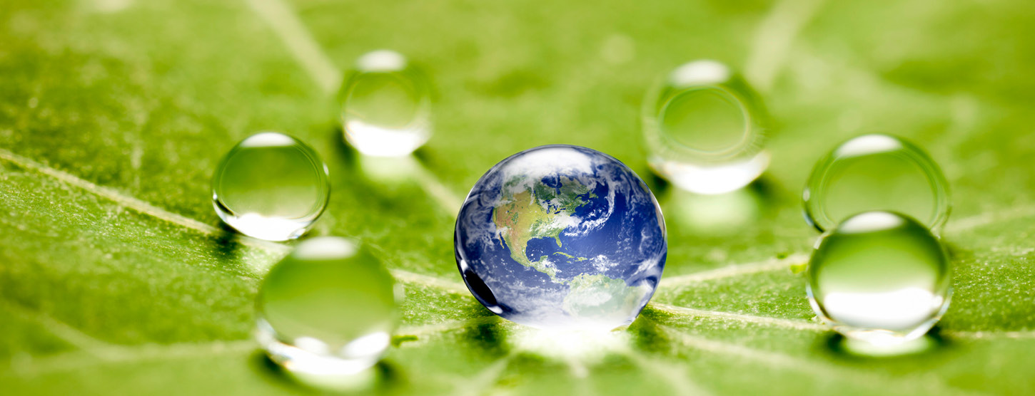 Die Weltkugel in einem Wassertropfen auf einem grünen Blatt.