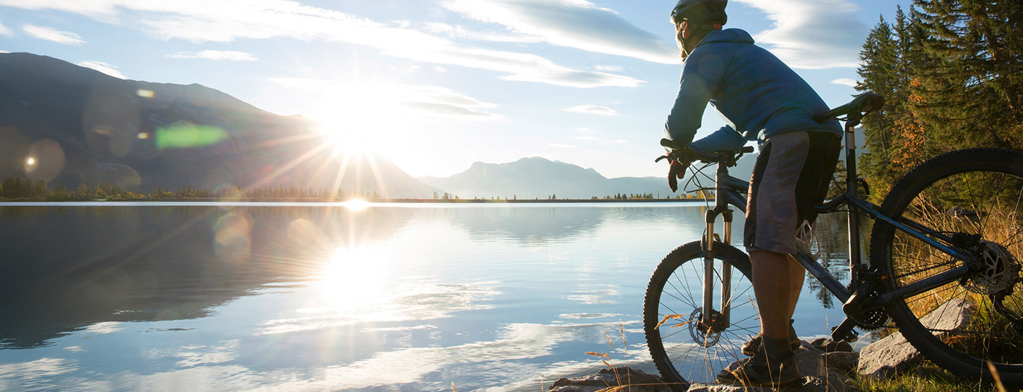 Ein Fahrradfahrer steht mit seinem Mountainbike vor einem großen See