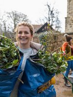Ein junges Mädchen hilf ehrenamtlich bei der Pflege eines Mauerstücks.