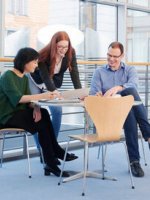 Personen arbeiten in einem hellen Konferenzraum gemeinsam vor einer Flip-Chart.