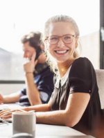 Eine Frau im Büro dreht sich lächelnd zu einer anderen Person.