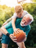 Junge spielt mit Opa Basketball.