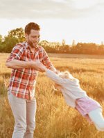 Vater spielt mit seiner Tochter auf einem Feld.