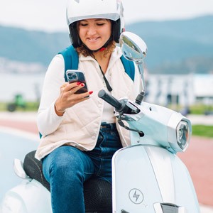 Eine junge Frau sitzt auf ihrem Elektroroller