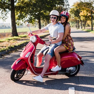Ein junges Paar sitzt auf einem Motorroller
