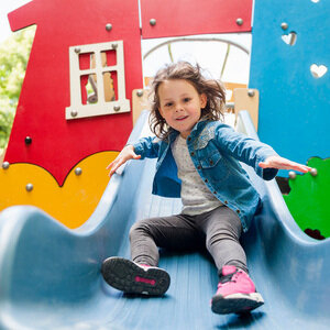 Ein Mädchen rutscht auf einer blauen Rutsche.