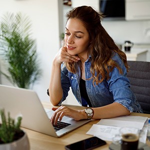 Eine junge Frau sitzt an ihrem Laptop.