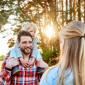 Eine Familie steht vor Bäumen und einem Feld.