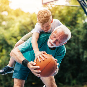 Junge spielt mit Opa Basketball.