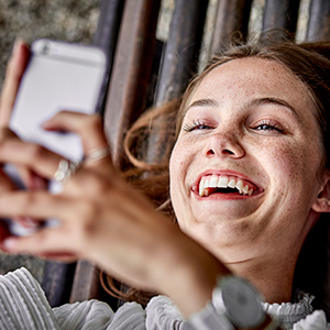 Eine junge Frau schaut auf ihr Handy und ist glücklich.