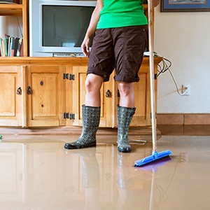 Eine Frau wischt Wasser aus einem überfluteten Haus.