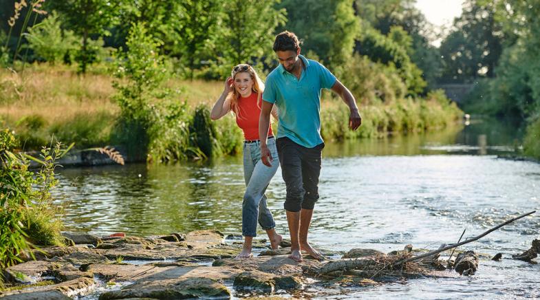 Junge Menschen gehen durch einen Fluss.