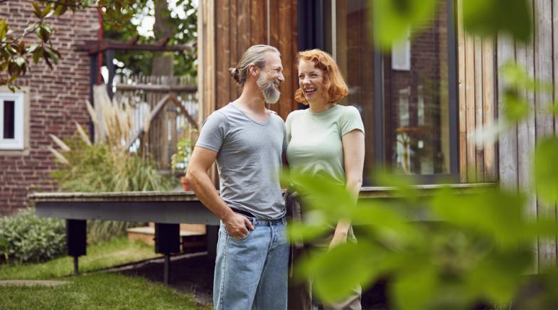 Ein Mann und eine Frau stehen vor ihrem Haus im Garten
