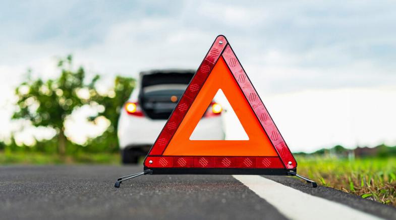 Warndreieck auf einer Landstraße hinter einem Auto.