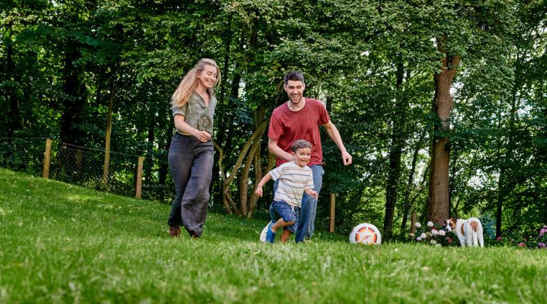 Eine Familie spielt Fußball im Garten.