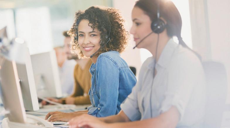 Zwei Frauen mit Headset im Büro.