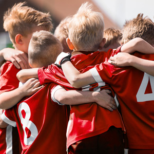 Kinder in Fußball-Trikots umarmen sich.