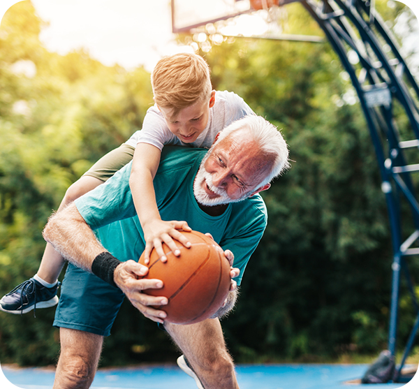 Junge spielt mit Opa Basketball.