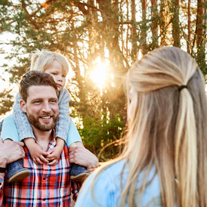 Eine Familie steht vor Bäumen und einem Feld.