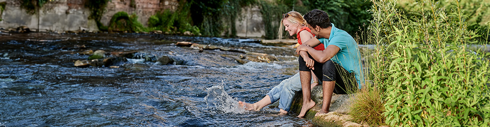 Junge Menschen gehen durch einen Fluss.