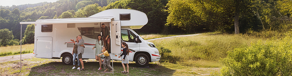 Eine Familie steigt auf einem Parkplatz aus dem Wohnmobil aus.
